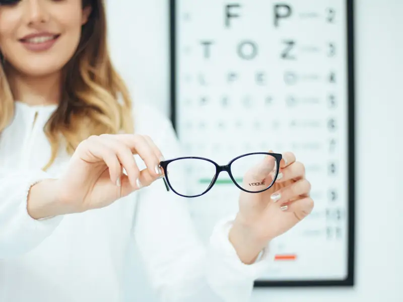 Lady holding glasses in eye exam